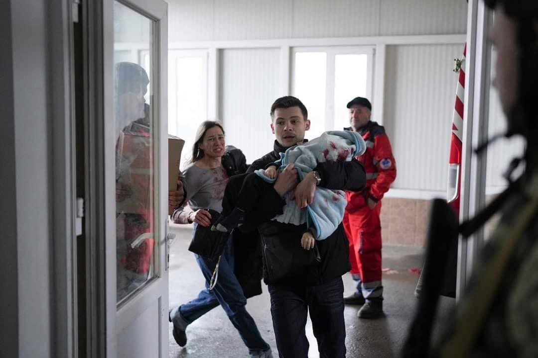 A man carries an injured child. Mariupol. Ukraine