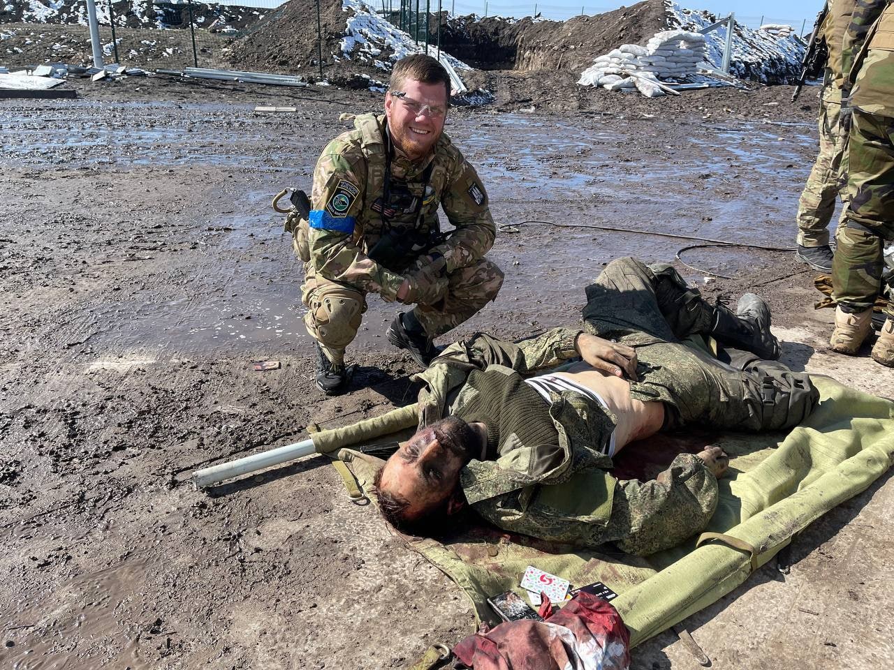 Ukrainian military poses against the backdrop of the corpse of a Russian soldier