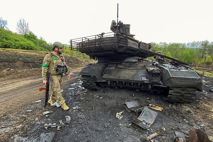 Soldier of the Armed Forces of Ukraine next to a destroyed Russian tank